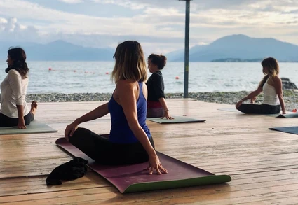 Individual yoga lesson at dawn in front of Lake Garda in Rivoltella